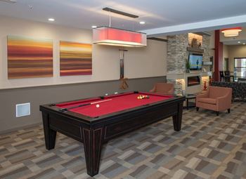 A pool table in a room with a chair and a television.